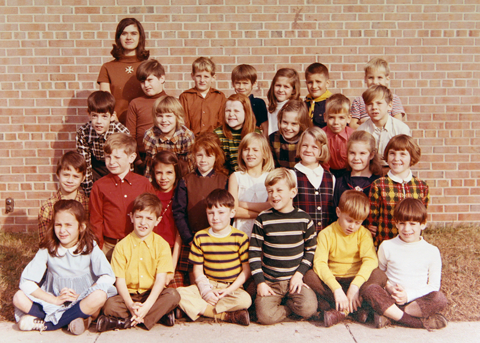 Photograph of students and their teacher posing in front of the school. 26 students are pictured.